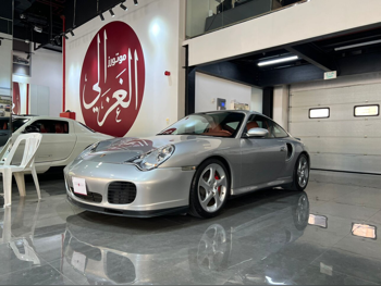 بورش  911  توربو  2003  اوتوماتيك  103,000 كم  6 سلندر  دفع خلفي  كوبيه \ سبورت  فضي